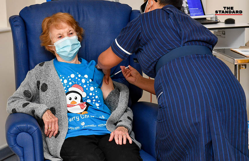 นางพยาบาลเมย์ พาร์สันส์ ฉีดวัคซีนโควิด-19 เข็มแรกให้ มากาเรต คีแนน วัย 90 ปี ที่ University Hospital เมืองโคเวนทรี สหราชอาณาจักร เมื่อวันที่ 8 ธันวาคม