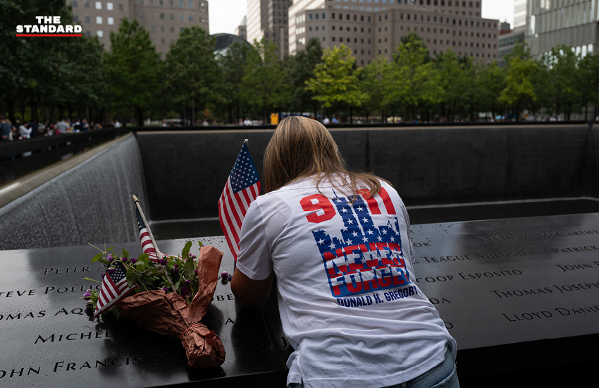 หญิงคนหนึ่งนำดอกไม้และธงชาติมาวางไว้เหนือรายชื่อของผู้เสียชีวิตจากเหตุการณ์ 9/11 ณ บริเวณ Ground Zero เพื่อไว้อาลัยแก่ผู้ที่จากไป เมื่อวันที่ 10 กันยายน 2023