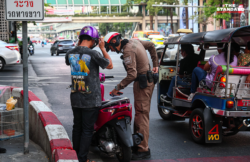 ตำรวจจราจรใช้ไฟฉายส่องเตือนผู้ขับขี่ที่จอดรถทับทางม้าลายบริเวณแยกราชประสงค์