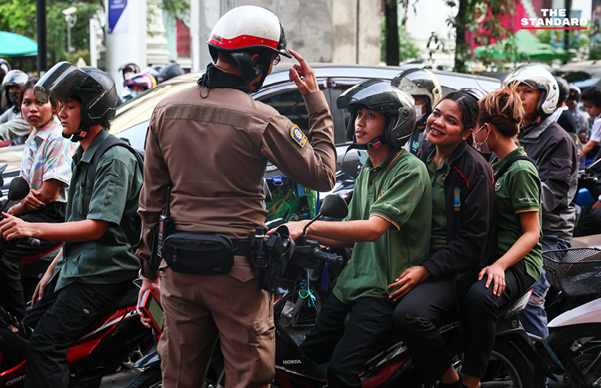 ตำรวจจราจรใช้ไฟฉายส่องเตือนผู้ขับขี่ที่จอดรถทับทางม้าลายบริเวณแยกราชประสงค์