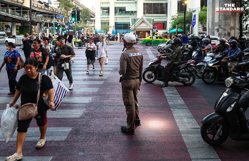 ตำรวจจราจรใช้ไฟฉายส่องเตือนผู้ขับขี่ที่จอดรถทับทางม้าลายบริเวณแยกราชประสงค์