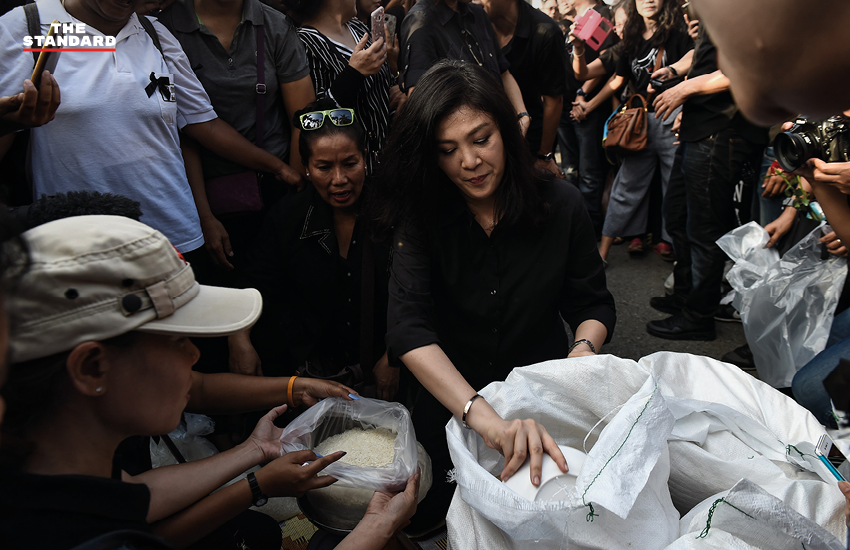 ยิ่งลักษณ์ กำลังตักข้าวสารเพื่อแจกถุงข้าวให้ประชาชน 