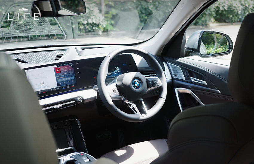 BMW iX1 L สีขาวหรือสีฟ้าที่จอดอยู่ในเมือง