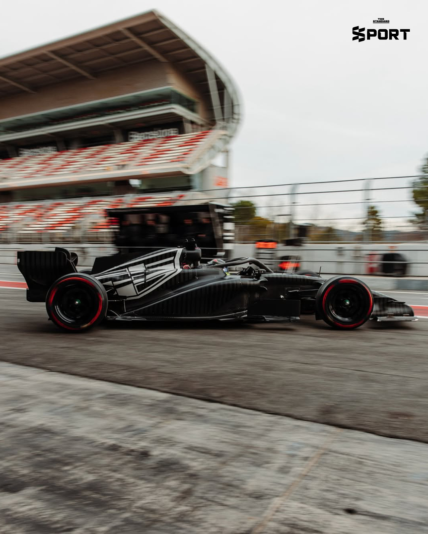 ภาพการแต่งกายของนักแข่งทีม Cadillac F1 พร้อมอุปกรณ์และโลโก้ทีมที่แสดงถึงสไตล์และความหรูหรา 1