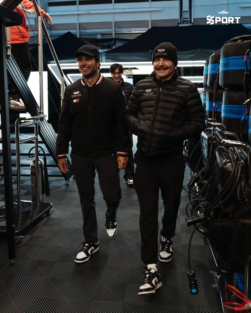 ภาพการแต่งกายของนักแข่งทีม Cadillac F1 พร้อมอุปกรณ์และโลโก้ทีมที่แสดงถึงสไตล์และความหรูหรา 2