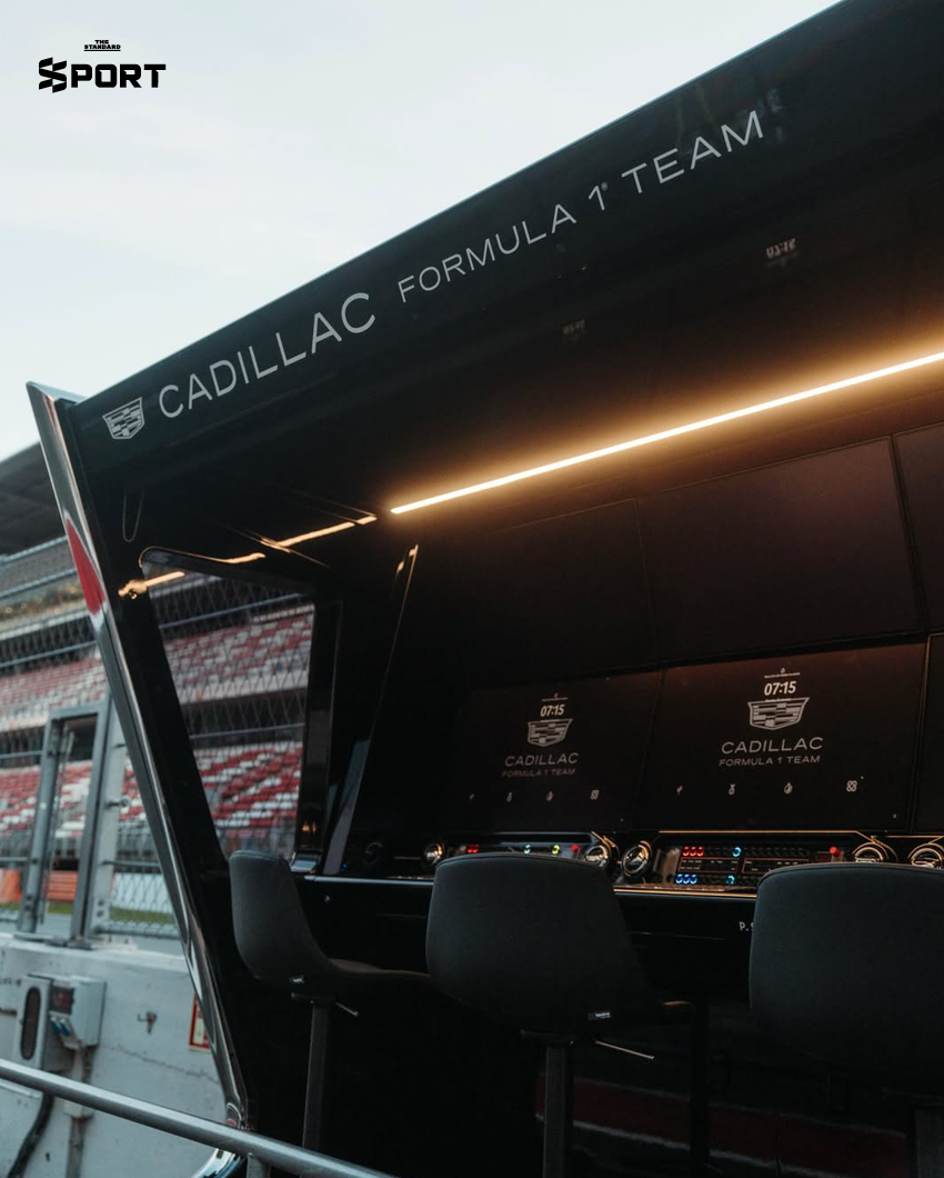 ภาพการแต่งกายของนักแข่งทีม Cadillac F1 พร้อมอุปกรณ์และโลโก้ทีมที่แสดงถึงสไตล์และความหรูหรา 3