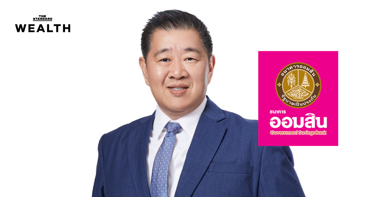 ทรงพล ชีวะปัญญาโรจน์ ในชุดสูท กำลังเซ็นเอกสารในพิธีแต่งตั้งเป็นผู้อำนวยการธนาคารออมสิน