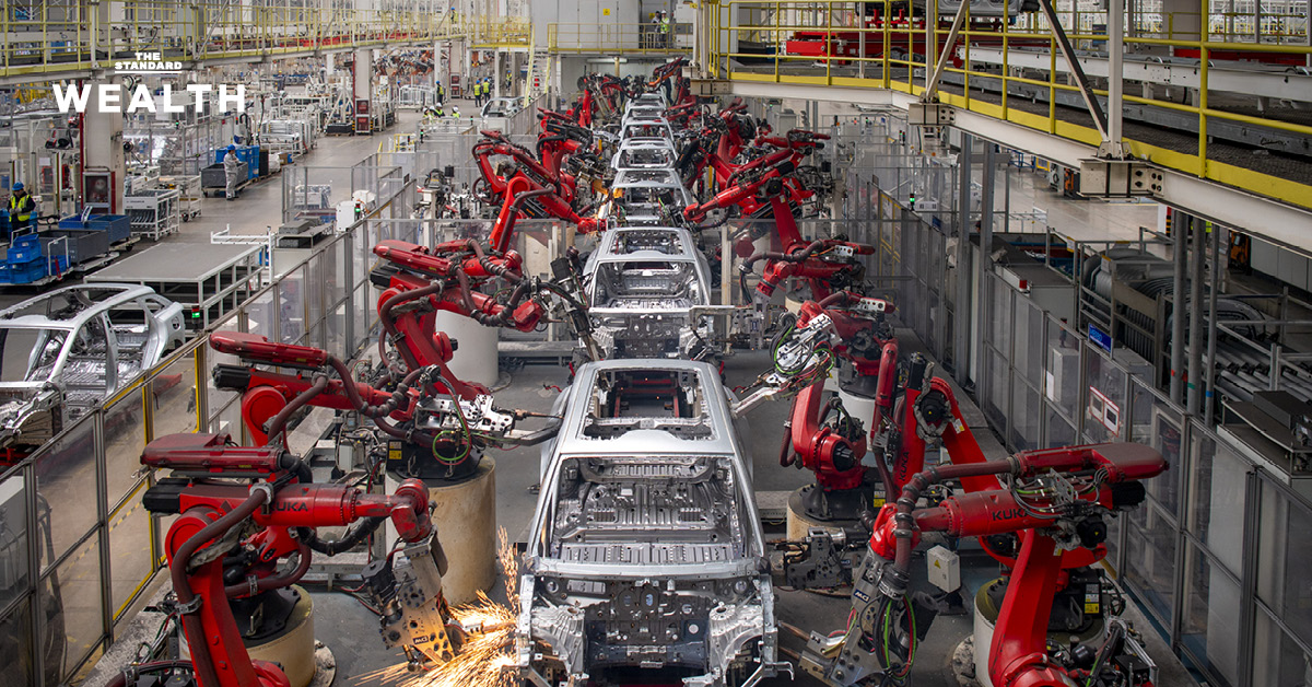 แขนกลกำลังทำงานในสายพานการผลิตรถยนต์ไฟฟ้า