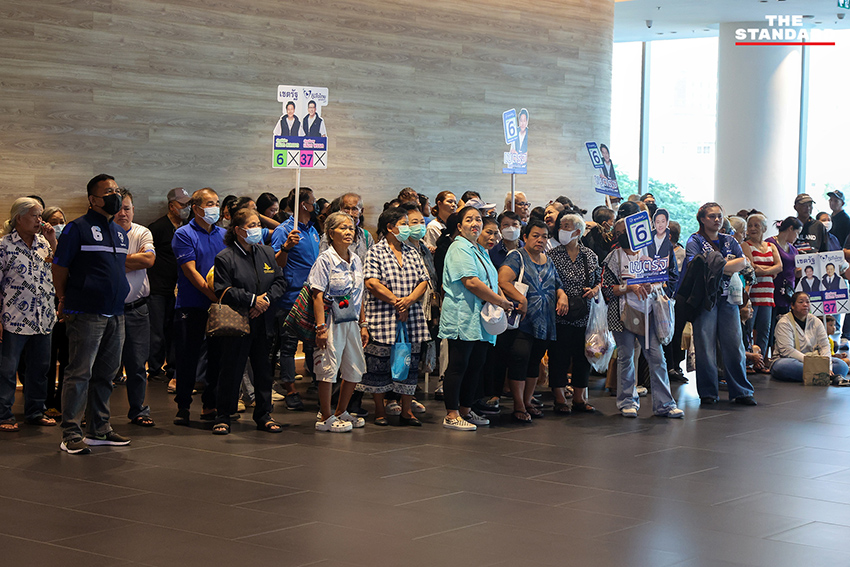 ประชาชนสวมเสื้อสีน้ำเงินร่วมฟังปราศรัยใหญ่พรรคภูมิใจไทย พร้อมถ่ายรูปกับป้ายนโยบายและภาพแกนนำ 10