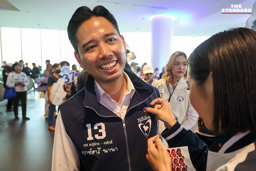 ประชาชนสวมเสื้อสีน้ำเงินร่วมฟังปราศรัยใหญ่พรรคภูมิใจไทย พร้อมถ่ายรูปกับป้ายนโยบายและภาพแกนนำ 2