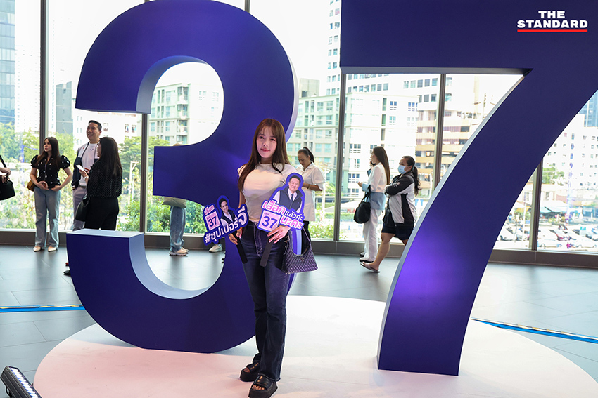 ประชาชนสวมเสื้อสีน้ำเงินร่วมฟังปราศรัยใหญ่พรรคภูมิใจไทย พร้อมถ่ายรูปกับป้ายนโยบายและภาพแกนนำ 7