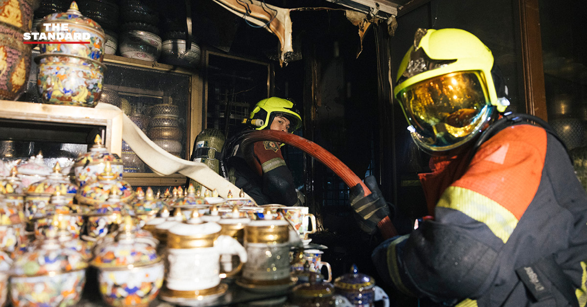 ภาพมุมกว้างเหตุเพลิงไหม้ร้านค้าในตลาดนัดจตุจักรยามค่ำคืน ขณะเจ้าหน้าที่ระดมกำลังฉีดน้ำสกัดเพลิง โดยมีควันไฟพวยพุ่งเหนือหลังคา