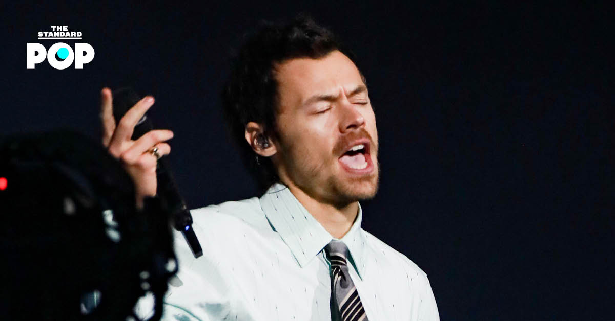 Harry Styles ในชุดสีดำกำลังแสดงดนตรีบนเวที