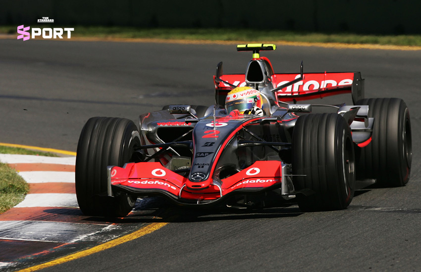 ลูอิส แฮมิลตัน ยืนยิ้มข้างรถแข่ง McLaren สีขาวแดง ในฤดูกาลเปิดตัวปี 2007 2