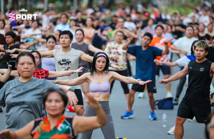 ภาพผู้คนกำลังเต้นแอโรบิกกลางแจ้งที่สวนลุมพินี โดยมีแมวมองดูเป็นกิมมิก 1