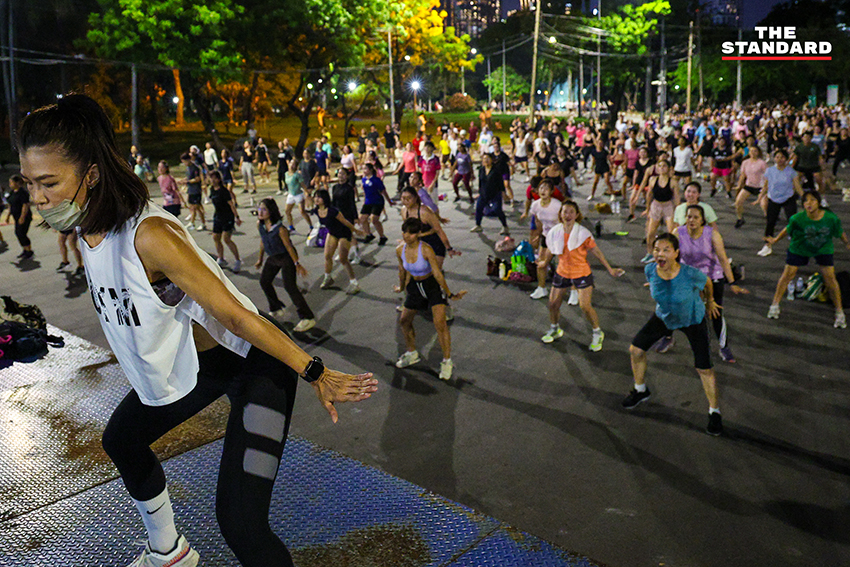 ภาพมุมกว้างของผู้คนจำนวนมากกำลังเต้นแอโรบิกอย่างสนุกสนานที่สวนลุมพินี 7
