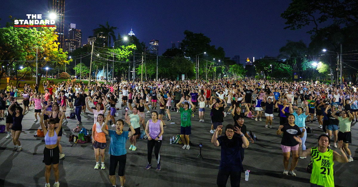 ภาพมุมกว้างของผู้คนจำนวนมากกำลังเต้นแอโรบิกอย่างสนุกสนานที่สวนลุมพินี