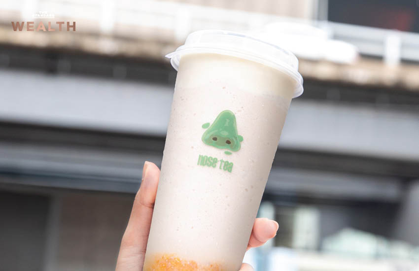 ธนกฤต ศรีพฤกษมาศ ผู้ก่อตั้ง Nose Tea ถ่ายภาพคู่เครื่องดื่มชาชีส พร้อมโลโก้จมูกสีเขียวอันเป็นเอกลักษณ์ของแบรนด์ 1