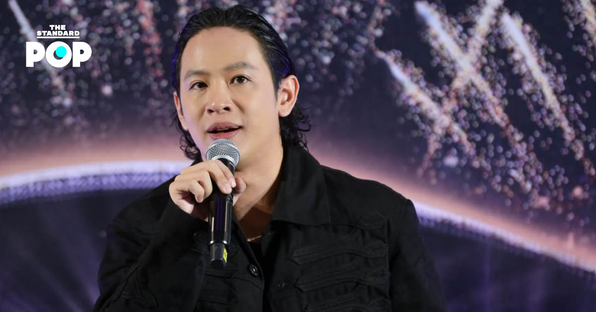 โอม ปัณฑพล ยืนในชุดสูท