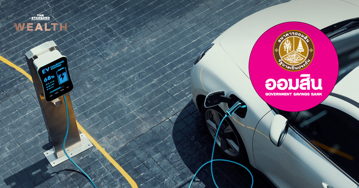 โลโก้ธนาคารออมสิน รถยนต์ไฟฟ้ากำลังชาร์จแบตเตอรี่ และแผงโซลาร์เซลล์บนหลังคา แสดงถึงสินเชื่อ Soft Loan GSB เพื่อพลังงานทางเลือก