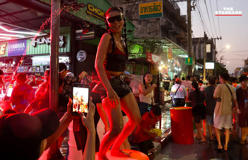 บรรยากาศผู้คนเล่นน้ำสงกรานต์อย่างคึกคักที่ถนนโชคชัย 4 พร้อมรถจักรยานยนต์และเสียงเพลง 4