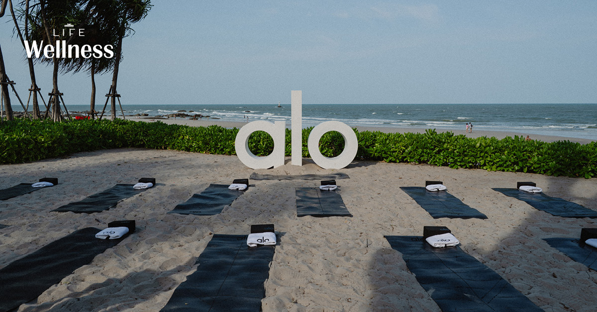 กลุ่มคนกำลังเล่นโยคะริมชายหาดหัวหินในกิจกรรมของ Alo ที่ The Standard, Hua Hin