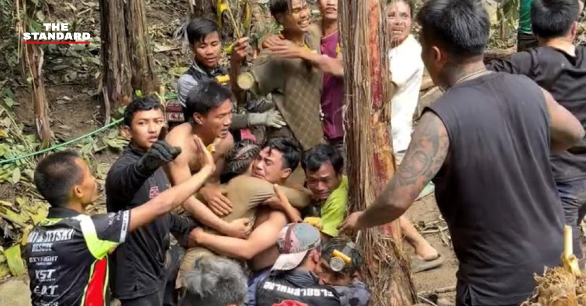 อาสาสมัครกู้ภัยนำตัวผู้ประสบภัยชาวลาวที่เปื้อนโคลนออกมาจากถ้ำ
