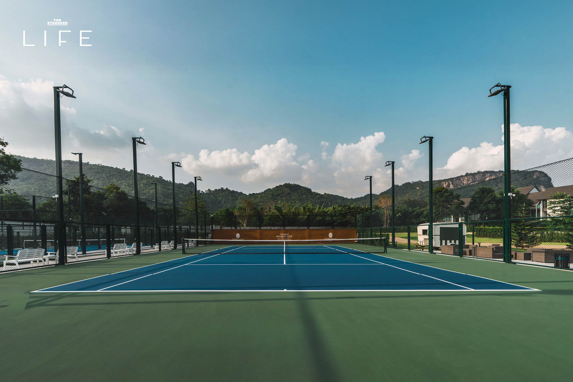 ภาพมุมกว้างของสนามเทนนิสหรือสนามแร็กเกตอื่นๆ ที่ Thames Racquet Yard เขาใหญ่ ท่ามกลางวิวภูเขาและบรรยากาศสไตล์อังกฤษ 1