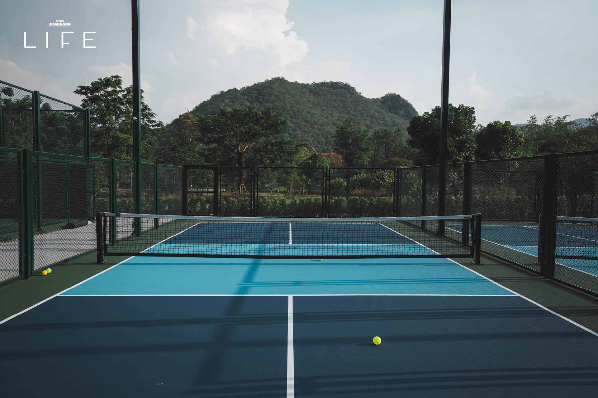 ภาพมุมกว้างของสนามเทนนิสหรือสนามแร็กเกตอื่นๆ ที่ Thames Racquet Yard เขาใหญ่ ท่ามกลางวิวภูเขาและบรรยากาศสไตล์อังกฤษ 6