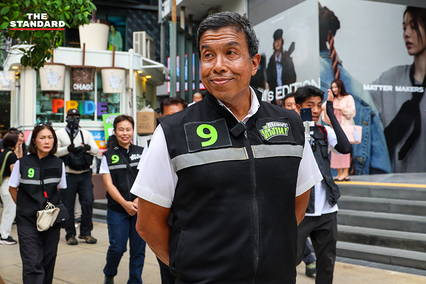 ชัชชาติ สิทธิพันธุ์ ผู้สมัครผู้ว่าฯ กทม. ทำท่าสัญลักษณ์เบอร์ 9 พร้อมป้ายหาเสียงศิลปะ 7