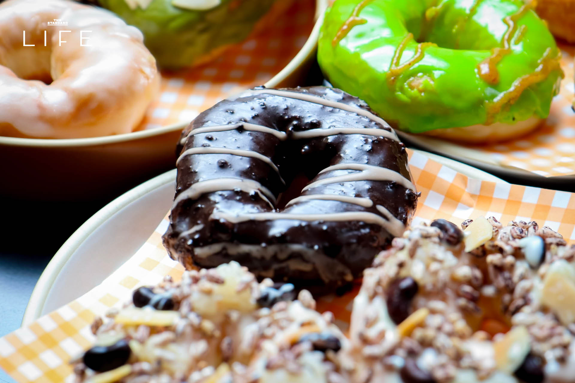 ภาพโดนัทโฮมเมด SODO Donut ที่ทำจากวัตถุดิบท้องถิ่น วางเรียงบนโต๊ะอย่างสวยงาม 16