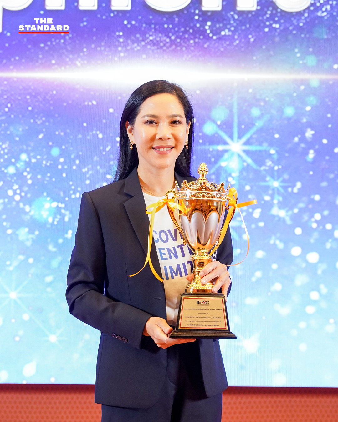 ดร.ดาริกา ลัทธพิพัฒน์ อธิการบดี DPU พร้อมโลโก้มหาวิทยาลัยและรางวัล IEAC 7