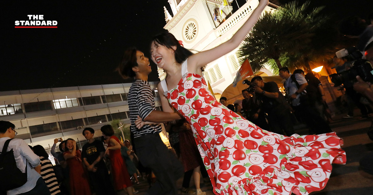 ภาพผู้คนกำลังเต้นรำอย่างสนุกสนานบนฟลอร์เต้นรำกลางแจ้งในสวนลุมพินี