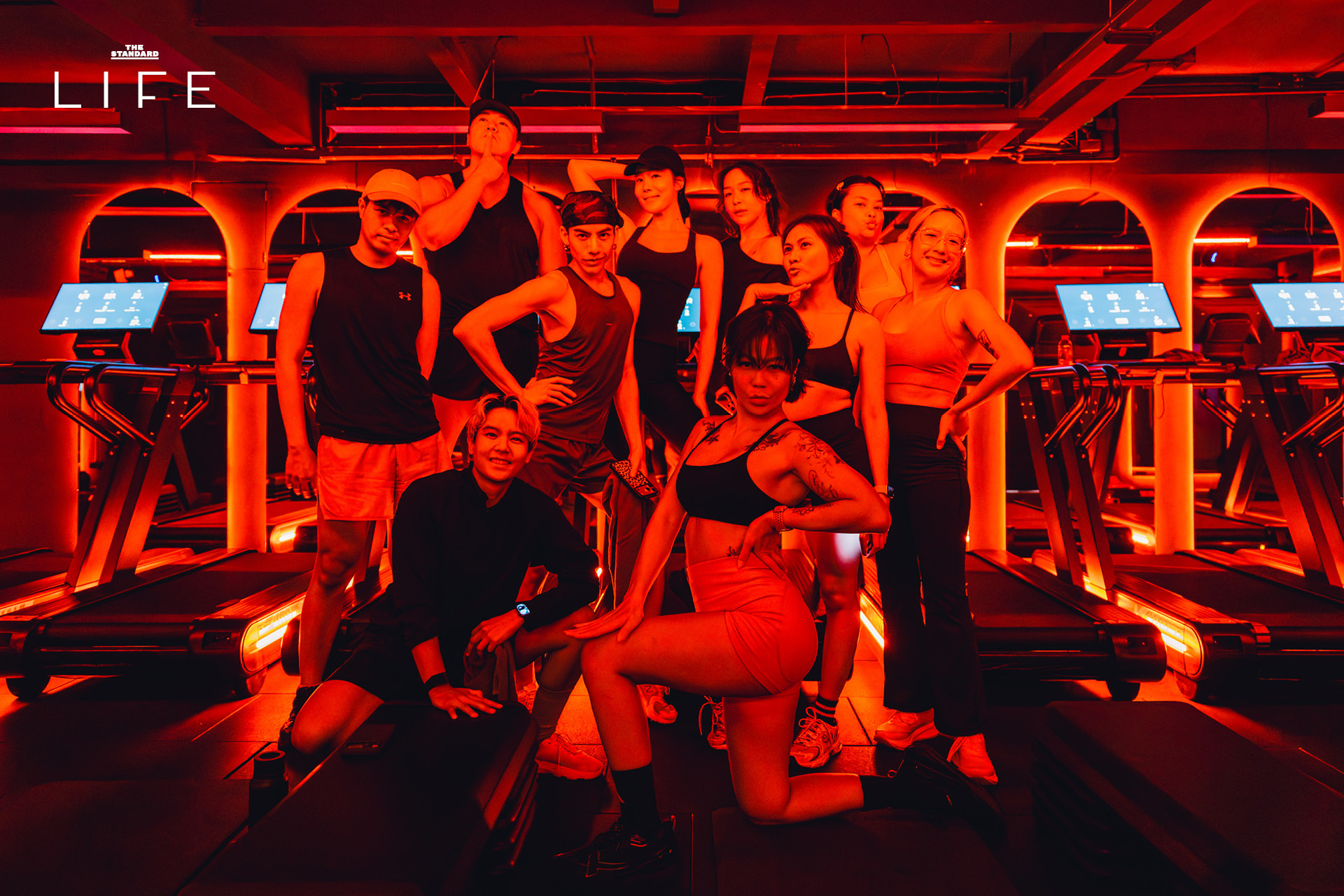 ผู้คนกำลังออกกำลังกายในคลาส HIIT + ASS & ABS ภายในยิม VAULT ที่ตกแต่งด้วยโทนสีแดง 23