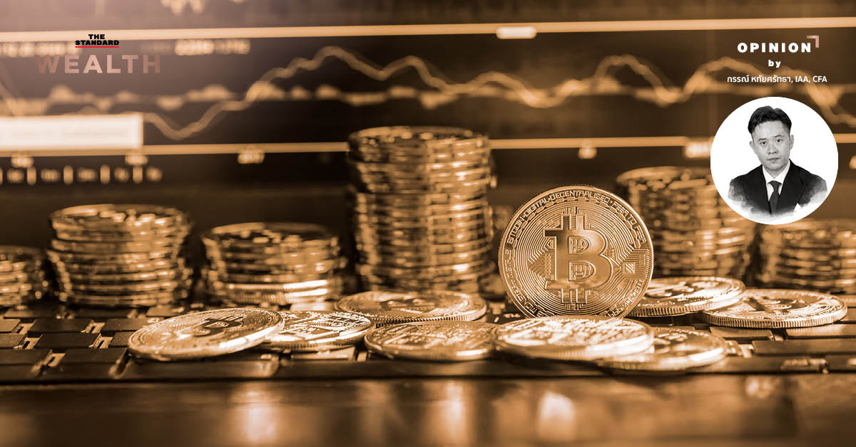 ภาพมือถือแสดงโลโก้ Bitcoin และเหรียญ Bitcoin วางอยู่บนโต๊ะ