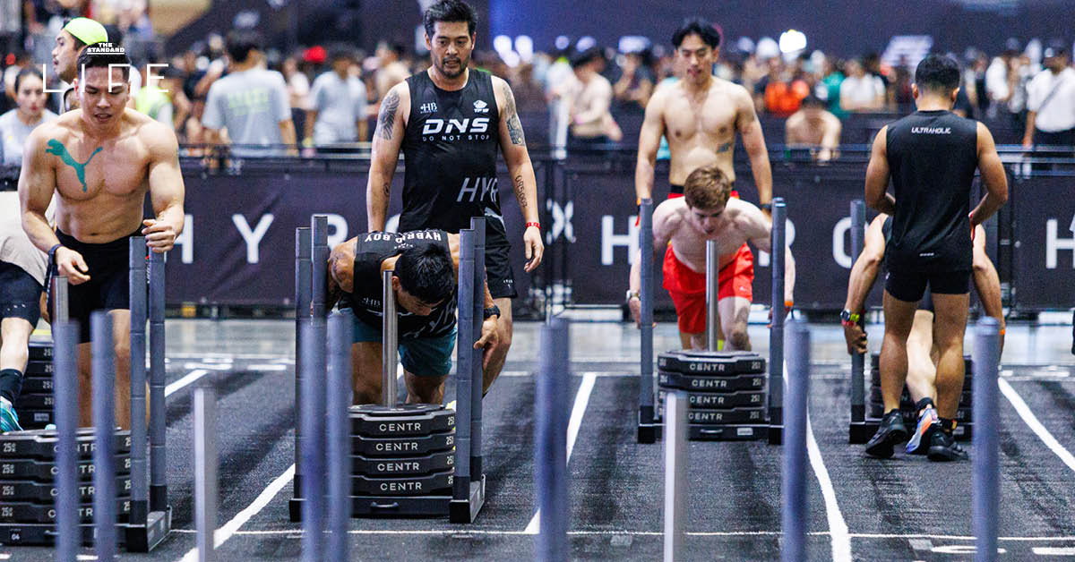 ต๊อด-ปิติ ภิรมย์ภักดี และโค้ชโค้ก ขจรศิลป์ วงษ์มา กำลังแข่งขัน HYROX Men Doubles โดยมี นุ่น-วรนุช ภิรมย์ภักดี ร่วมเชียร์