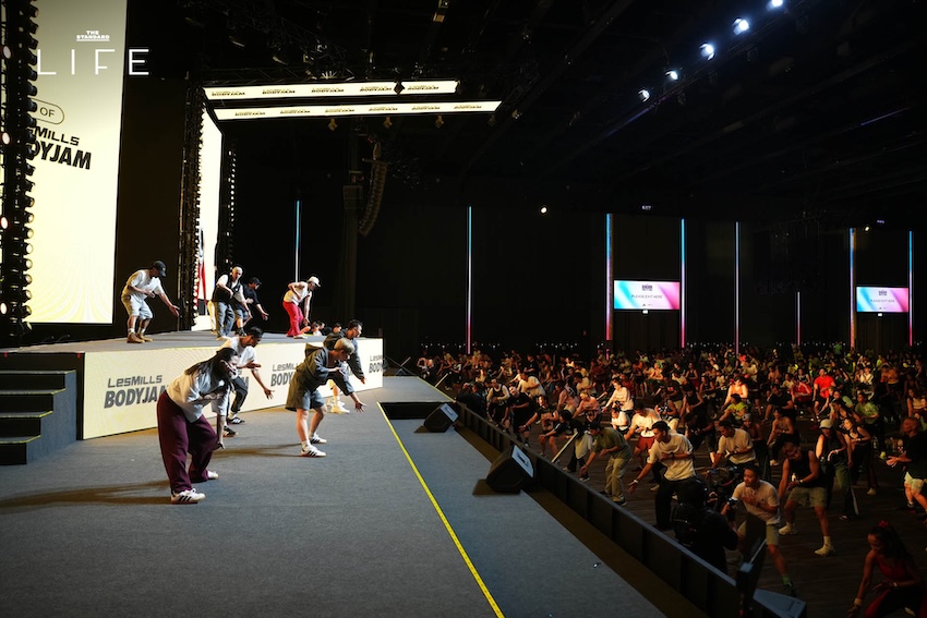 ภาพบรรยากาศงาน LES MILLS LIVE Bangkok 2026 x adidas ที่มีผู้คนจำนวนมากกำลังออกกำลังกายในฮอลล์ขนาดใหญ่ 1