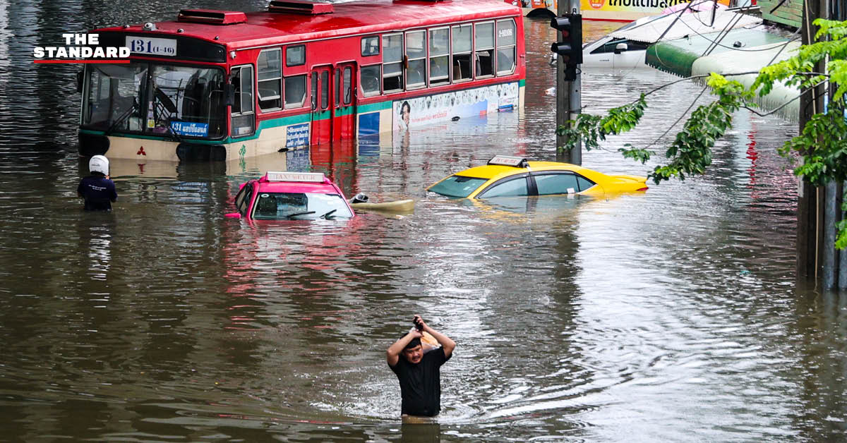 ภาพประชาชนเดินลุยน้ำท่วมสูงในชุมชนบางกะปิ ถนนและบ้านเรือนถูกน้ำท่วมขัง