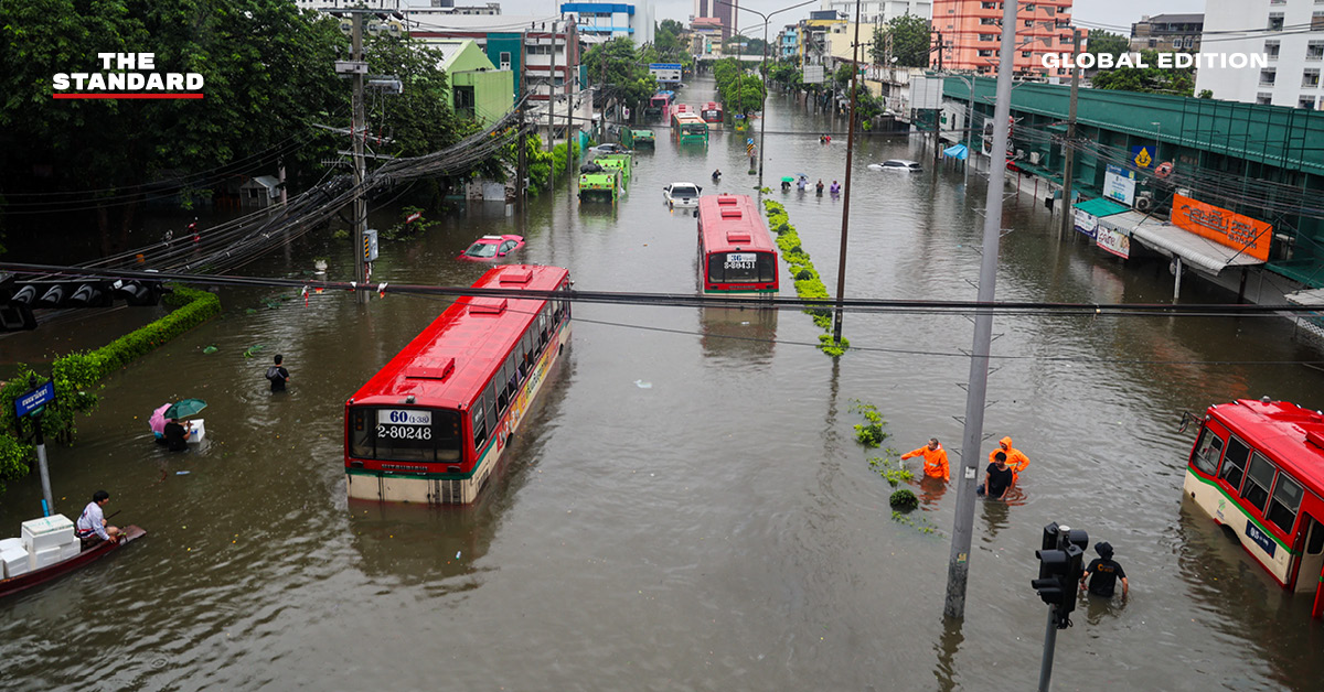 ภาพถนนในกรุงเทพฯ ที่ถูกน้ำท่วมขัง มีรถยนต์และผู้คนสัญจรผ่าน