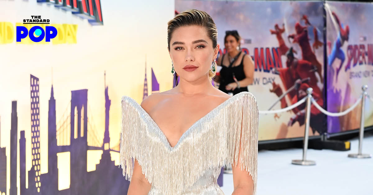 Florence Pugh นักแสดงสาวในชุดสีดำกำลังยิ้มและโบกมือบนพรมแดง
