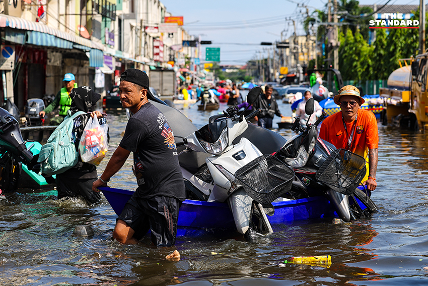 ภาพชาวบ้านในชุมชนเคหะร่มเกล้าใช้กะละมัง เรือเล็ก และรถกระบะสัญจรท่ามกลางน้ำท่วมสูง 1