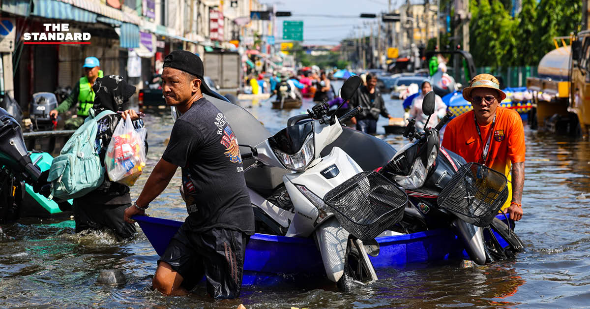 ภาพชาวบ้านในชุมชนเคหะร่มเกล้าใช้กะละมัง เรือเล็ก และรถกระบะสัญจรท่ามกลางน้ำท่วมสูง