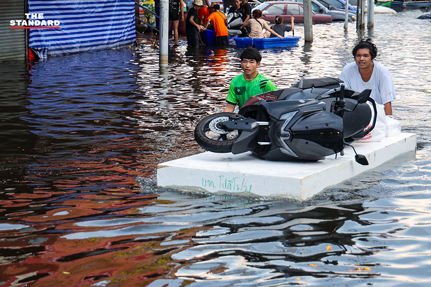 ภาพชาวบ้านในชุมชนเคหะร่มเกล้าใช้กะละมัง เรือเล็ก และรถกระบะสัญจรท่ามกลางน้ำท่วมสูง 10
