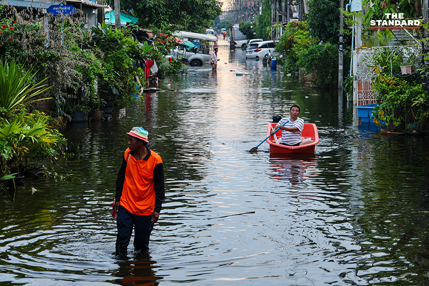 ภาพชาวบ้านในชุมชนเคหะร่มเกล้าใช้กะละมัง เรือเล็ก และรถกระบะสัญจรท่ามกลางน้ำท่วมสูง 16
