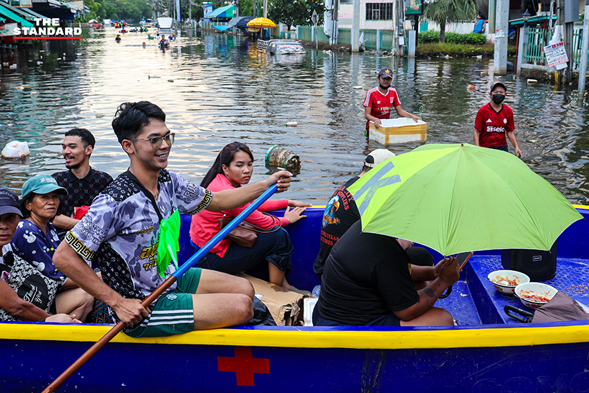 ภาพชาวบ้านในชุมชนเคหะร่มเกล้าใช้กะละมัง เรือเล็ก และรถกระบะสัญจรท่ามกลางน้ำท่วมสูง 18
