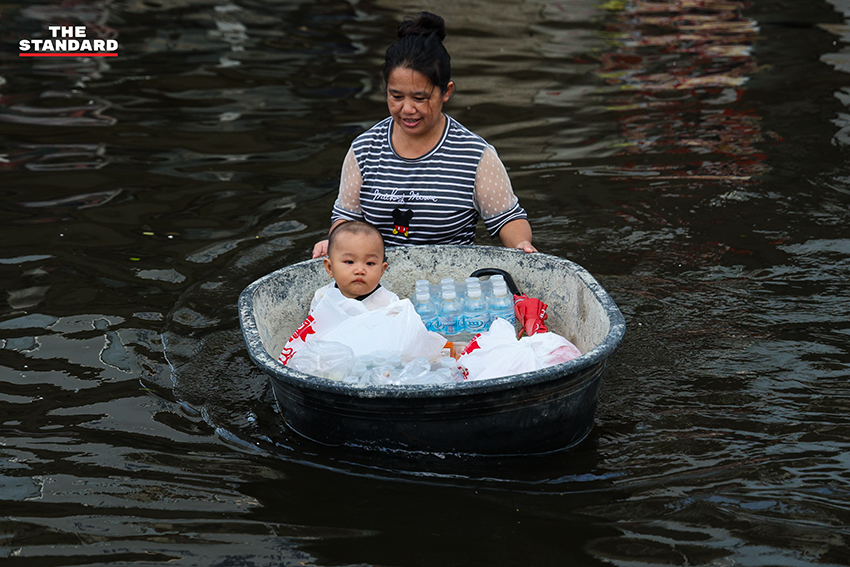 ภาพชาวบ้านในชุมชนเคหะร่มเกล้าใช้กะละมัง เรือเล็ก และรถกระบะสัญจรท่ามกลางน้ำท่วมสูง 2