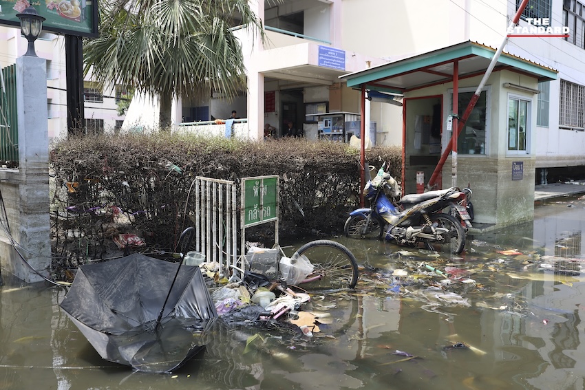 ประชาชนกำลังทำความสะอาดบ้านเรือนและถนนที่เต็มไปด้วยโคลนและขยะในเคหะร่มเกล้าหลังน้ำท่วม 15