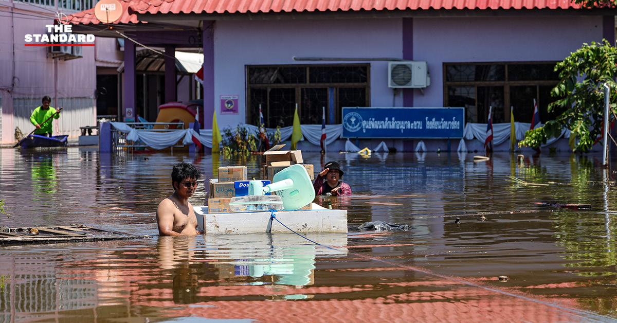 ภาพมุมกว้างแสดงสถานการณ์น้ำท่วมในอำเภอคลองเขื่อน จังหวัดฉะเชิงเทรา เจ้าหน้าที่เร่งเสริมแนวคันกั้นน้ำ และชาวบ้านใช้เรือสัญจร
